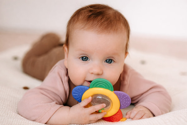 Baby chewing on colorful BIS-approved teether toy — Mama's Care certified safe rattles and teethers for newborns 0-6 months
